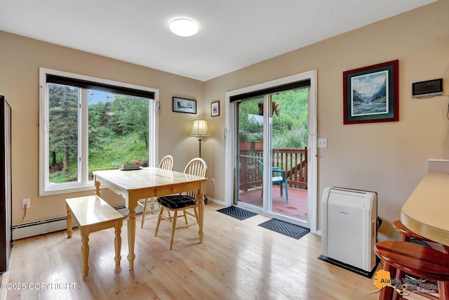 dining room featuring baseboards, light wood-style floors, a healthy amount of sunlight, and a baseboard radiator