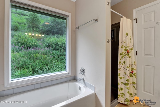 bathroom featuring a garden tub, curtained shower, and a wealth of natural light