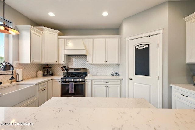 2153 S Withers Rd, Wasilla, AK 99654 - kitchen featuring stainless steel range with gas stovetop, custom exhaust hood, decorative backsplash, light stone counters, and recessed lighting