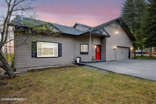 view of front of house featuring a garage, asphalt driveway, and a yard