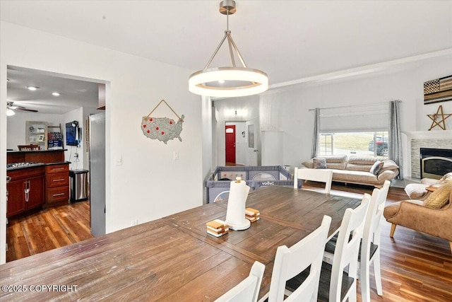 dining room featuring wood finished floors, a ceiling fan, and a fireplace