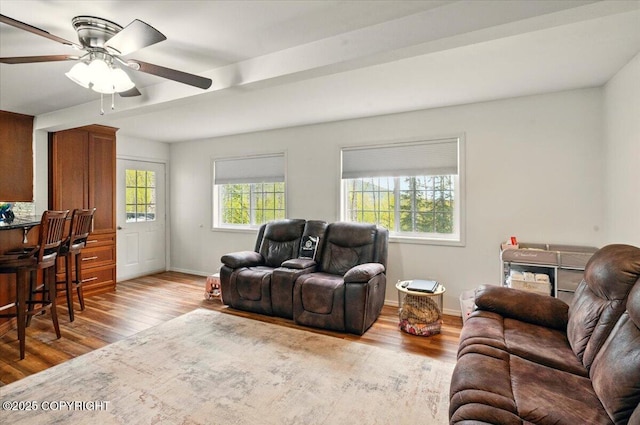 living area featuring wood finished floors, ceiling fan, and baseboards
