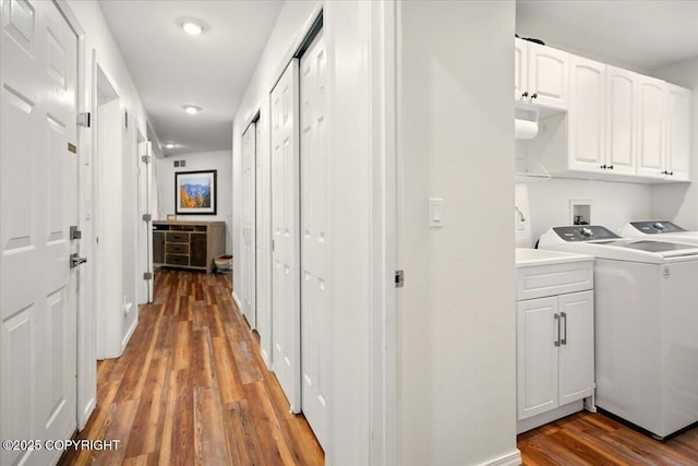 clothes washing area with cabinet space, light wood-style flooring, washing machine and clothes dryer, and recessed lighting