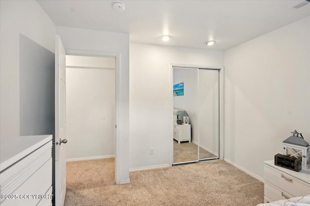 unfurnished bedroom featuring light colored carpet, a closet, and baseboards