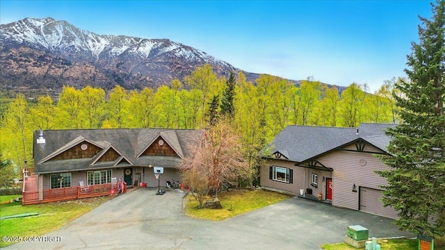 view of front of house featuring asphalt driveway, a porch, a forest view, and a mountain view