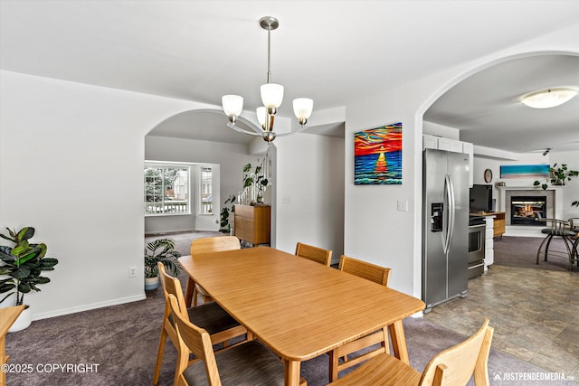 1734 Concord Hill Dr, Anchorage, AK 99515 - dining area featuring baseboards, arched walkways, an inviting chandelier, and a glass covered fireplace