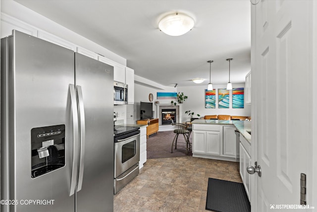 1734 Concord Hill Dr, Anchorage, AK 99515 - kitchen with stainless steel appliances, a glass covered fireplace, stone finish flooring, white cabinets, and open floor plan