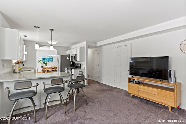 1734 Concord Hill Dr, Anchorage, AK 99515 - kitchen featuring light stone counters, a breakfast bar, stainless steel appliances, dark carpet, and a peninsula