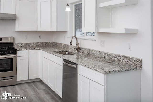 kitchen with stainless steel appliances, a sink, white cabinetry, wood finished floors, and extractor fan