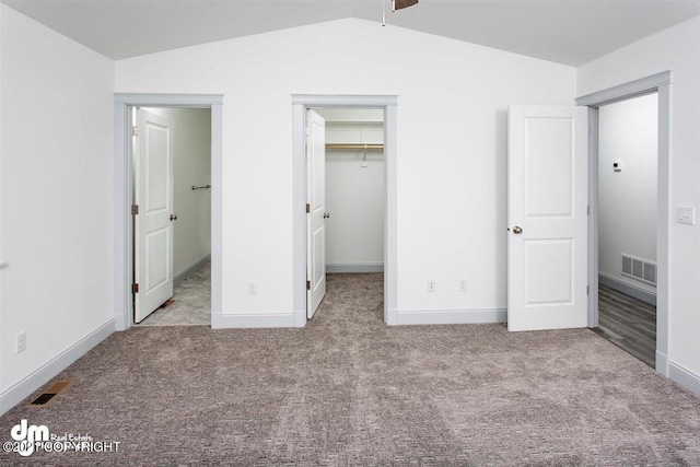 unfurnished bedroom with carpet, lofted ceiling, a walk in closet, baseboards, and a closet