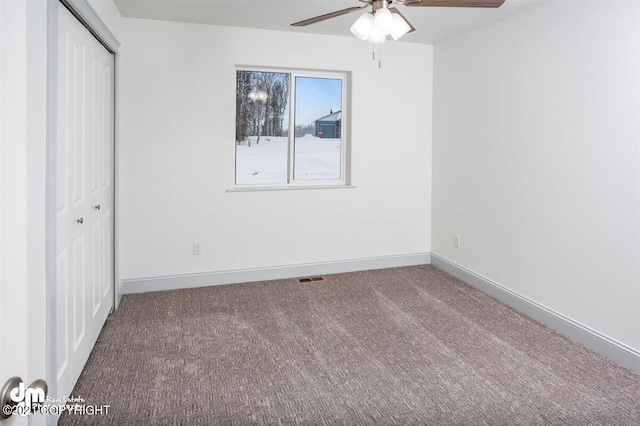 unfurnished bedroom with a closet, carpet flooring, baseboards, and ceiling fan