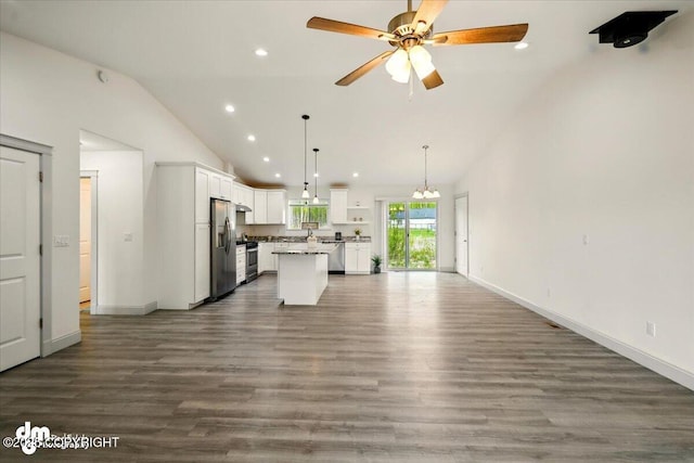 kitchen with stainless steel appliances, lofted ceiling, open floor plan, white cabinets, and ceiling fan