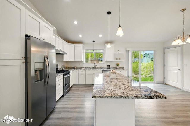 kitchen featuring stainless steel appliances, under cabinet range hood, open shelves, a sink, and a kitchen island