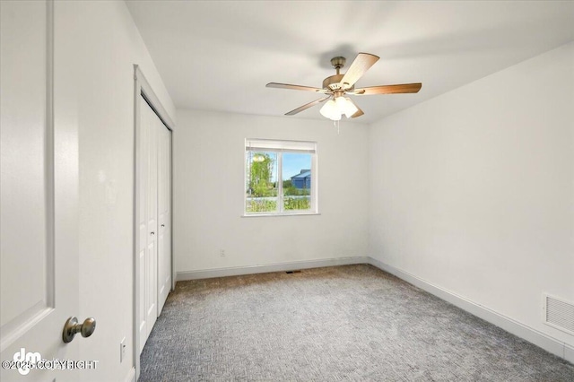 unfurnished bedroom featuring carpet flooring, a closet, baseboards, and a ceiling fan