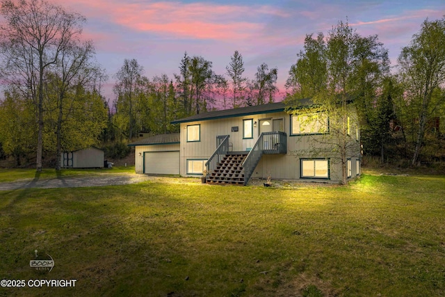back of house at dusk featuring a yard, dirt driveway, and an outbuilding