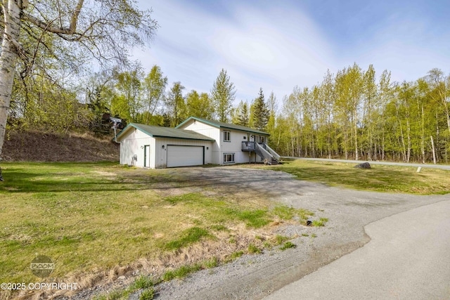 view of side of property featuring driveway, a yard, and an attached garage