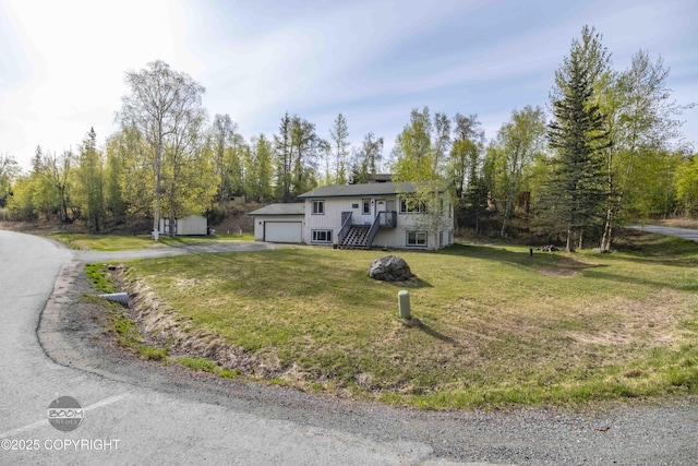 raised ranch featuring asphalt driveway and a front lawn