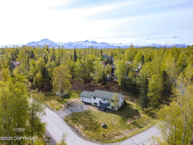 view of subject property with a mountain backdrop and a heavily wooded area