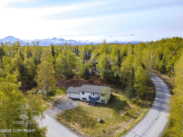aerial view of property and surrounding area featuring a heavily wooded area and a mountainous background
