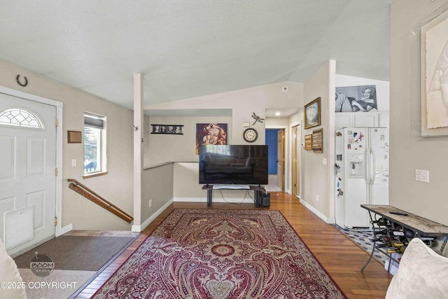 foyer entrance with wood finished floors, lofted ceiling, and baseboards