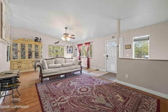 living room featuring ceiling fan, wood finished floors, baseboards, and lofted ceiling