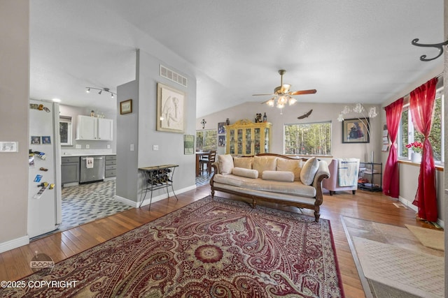living room with ceiling fan, hardwood / wood-style floors, baseboards, and lofted ceiling