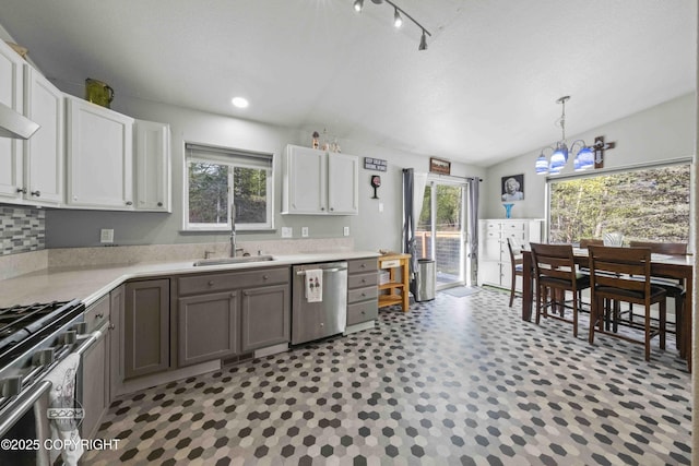kitchen featuring stainless steel appliances, a sink, a chandelier, lofted ceiling, and light countertops