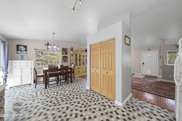 dining area featuring a chandelier, lofted ceiling, and baseboards