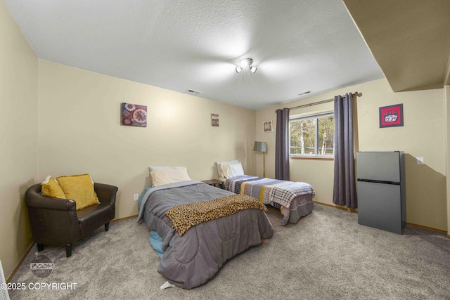 bedroom featuring freestanding refrigerator, carpet floors, baseboards, and a textured ceiling