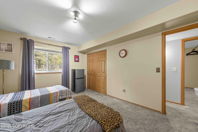 carpeted bedroom featuring freestanding refrigerator, a closet, and baseboards