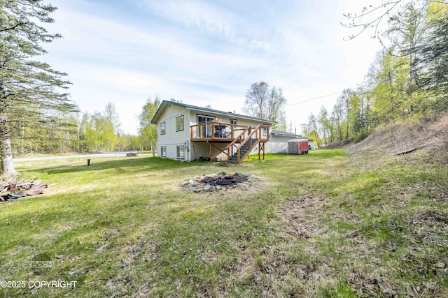 rear view of house with a fire pit, a wooden deck, stairway, and a yard
