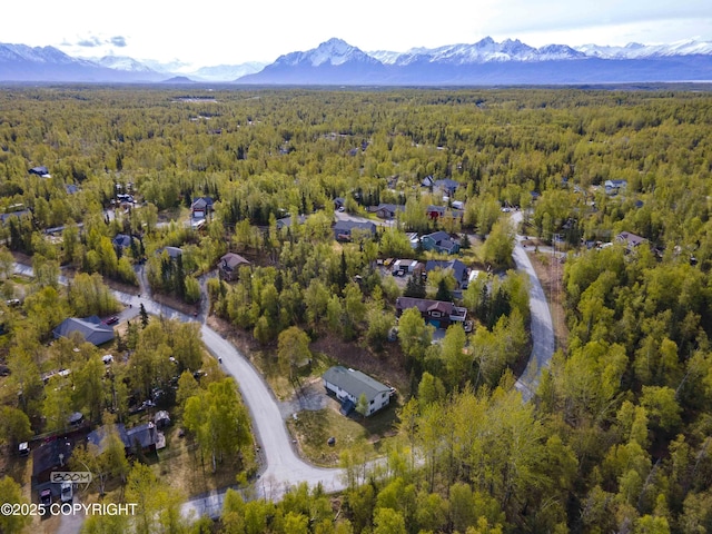 aerial view of property and surrounding area featuring a forest and a mountain backdrop