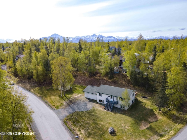 view from above of property featuring a mountain backdrop and a heavily wooded area