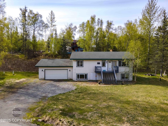 view of front of home with an attached garage, dirt driveway, stairs, and a front yard