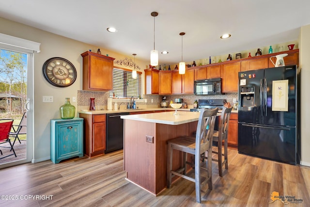 3690 S Granite Ln, Wasilla, AK 99654 - kitchen with black appliances, light wood-style floors, tasteful backsplash, light countertops, and a center island