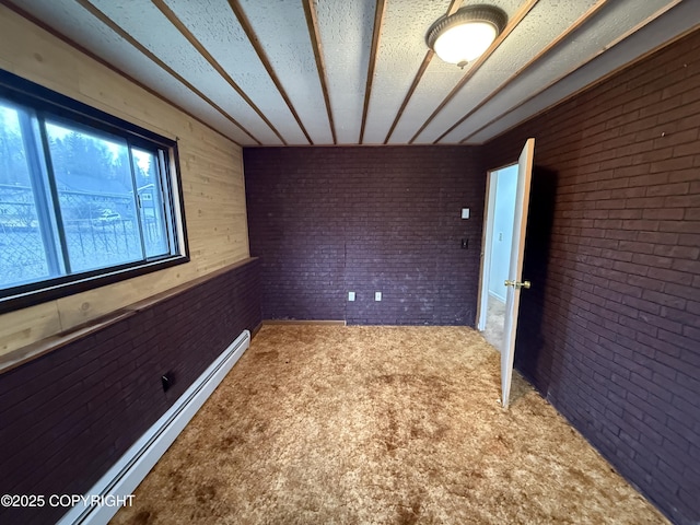 carpeted empty room with a baseboard heating unit and brick wall
