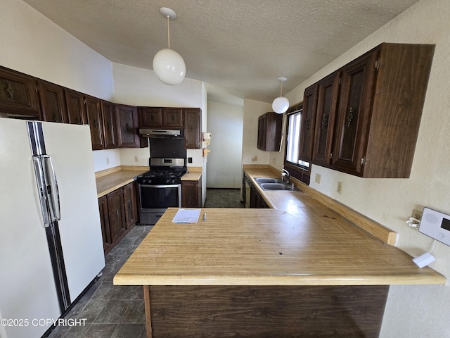 kitchen with dark brown cabinets, a sink, stainless steel range with gas stovetop, freestanding refrigerator, and under cabinet range hood