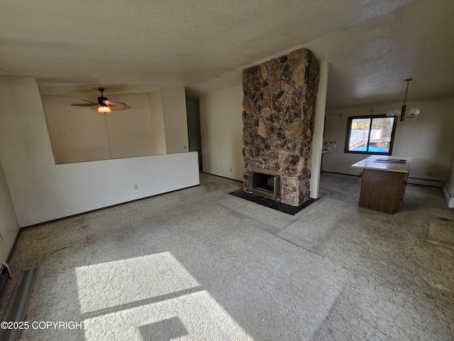 unfurnished living room featuring a textured ceiling, a baseboard heating unit, a stone fireplace, and ceiling fan with notable chandelier