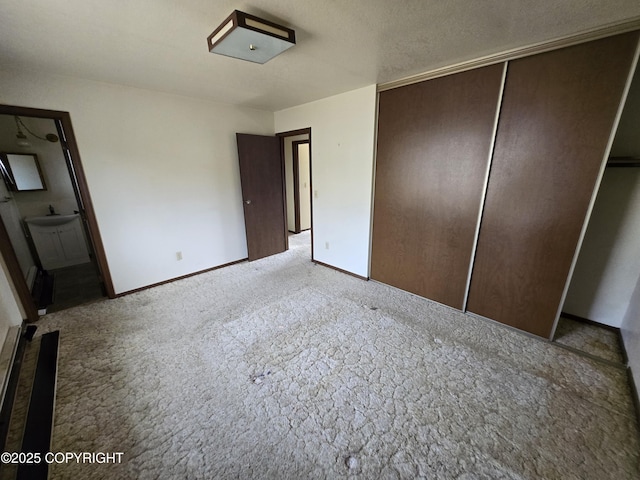 unfurnished bedroom featuring baseboards, carpet, a closet, and connected bathroom