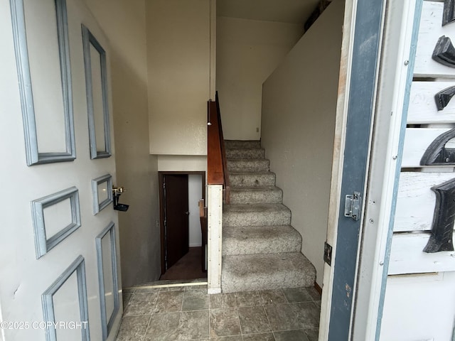 stairway featuring baseboards and stone finish floor