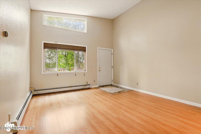 2631 Palmer Ct # C6, Anchorage, AK 99508 - empty room with wood finished floors, a baseboard heating unit, baseboards, and a high ceiling