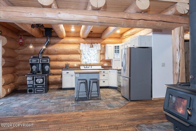 5920 Old Valdez Trl, Salcha, AK 99714 - kitchen featuring a wood stove, stainless steel appliances, a wood ceiling with exposed beams, white cabinets, and a center island