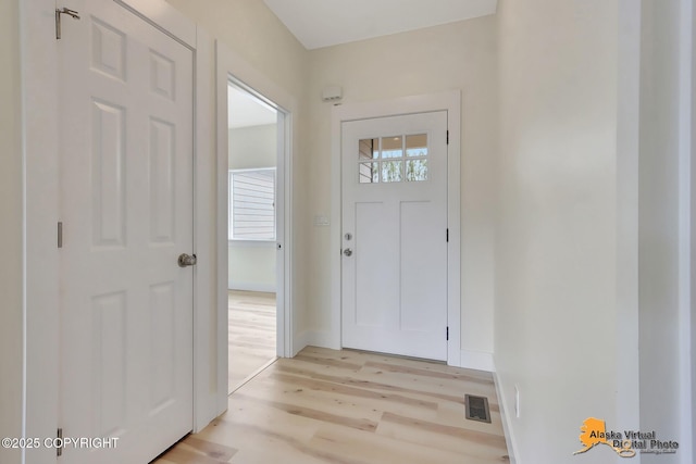 foyer with baseboards, light wood finished floors, and visible vents