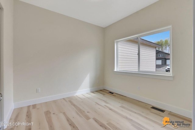 empty room with baseboards, wood finished floors, and visible vents
