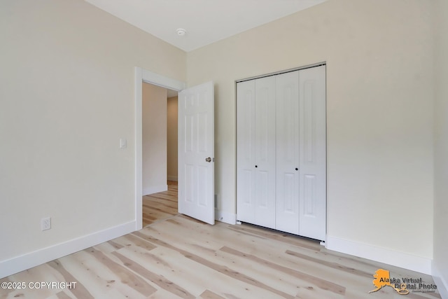 unfurnished bedroom featuring baseboards, a closet, and light wood-style flooring