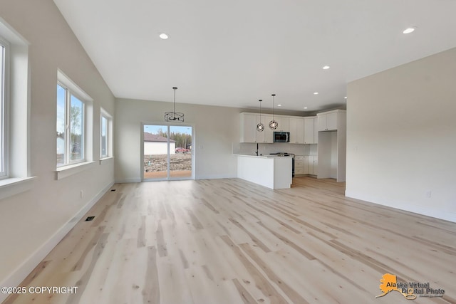 unfurnished living room featuring light wood-style floors, recessed lighting, baseboards, and a wealth of natural light