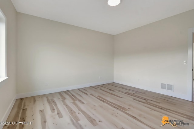 unfurnished room featuring visible vents, baseboards, and wood finished floors