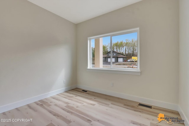 spare room featuring baseboards, visible vents, and wood finished floors