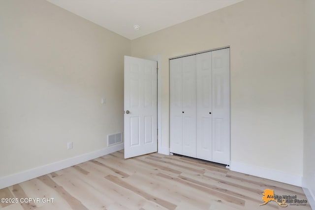 unfurnished bedroom with baseboards, visible vents, light wood-style flooring, and a closet