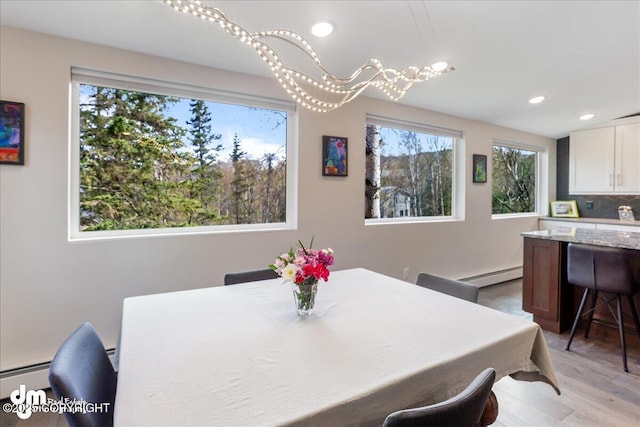dining room featuring light wood-type flooring, a baseboard radiator, and recessed lighting